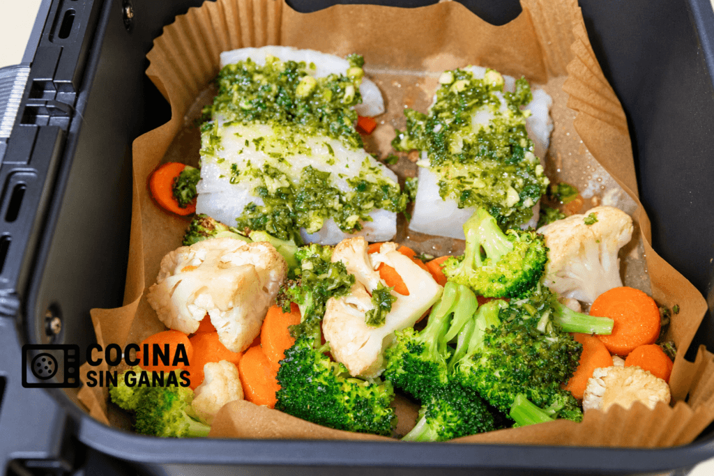 Bacalao y verduras juntos en la cesta de la freidora de aire